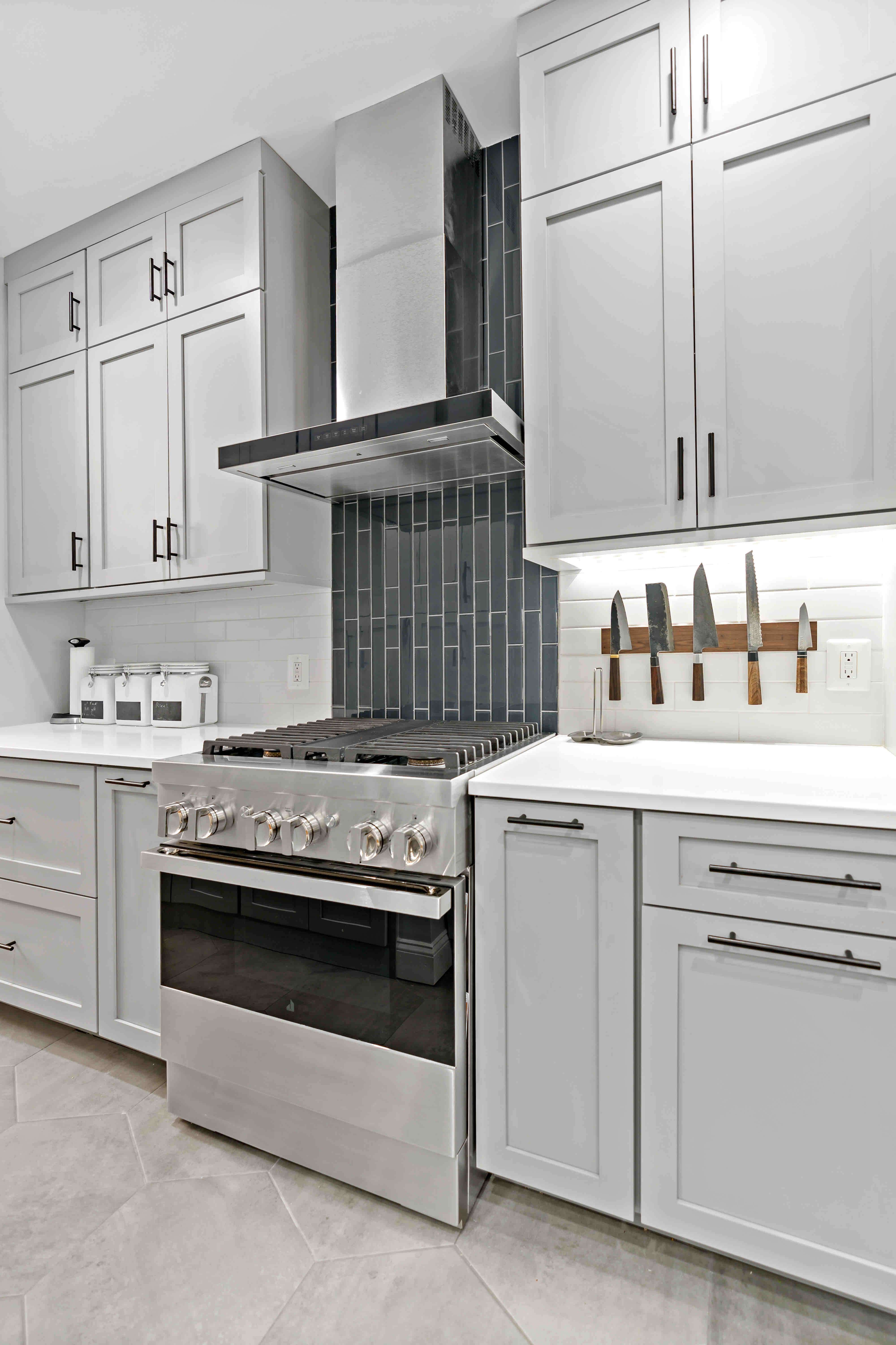 Light grey cabinets and dark grey backsplash behinds stove