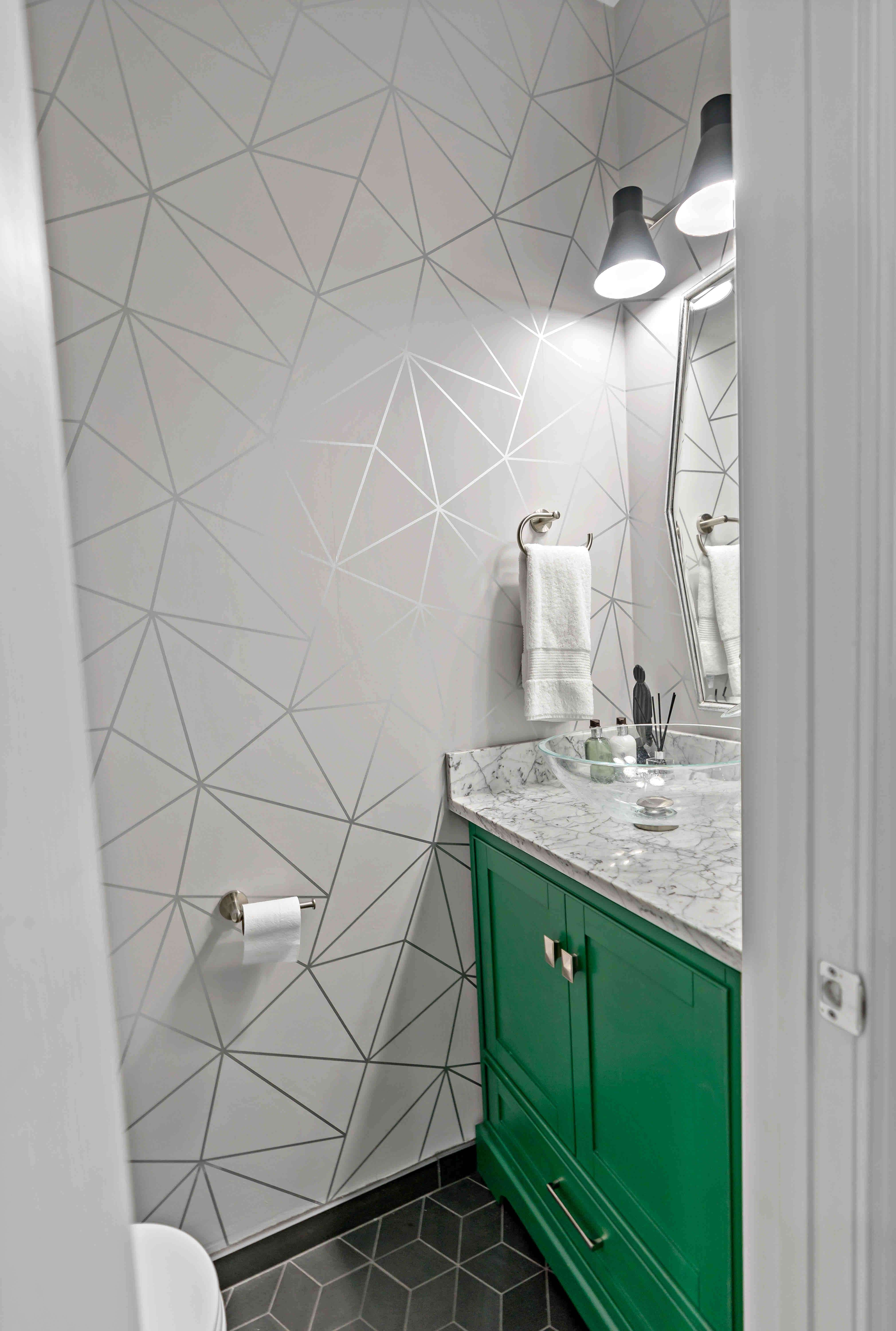 Small half bathroom with green cabinets and geometric wall design