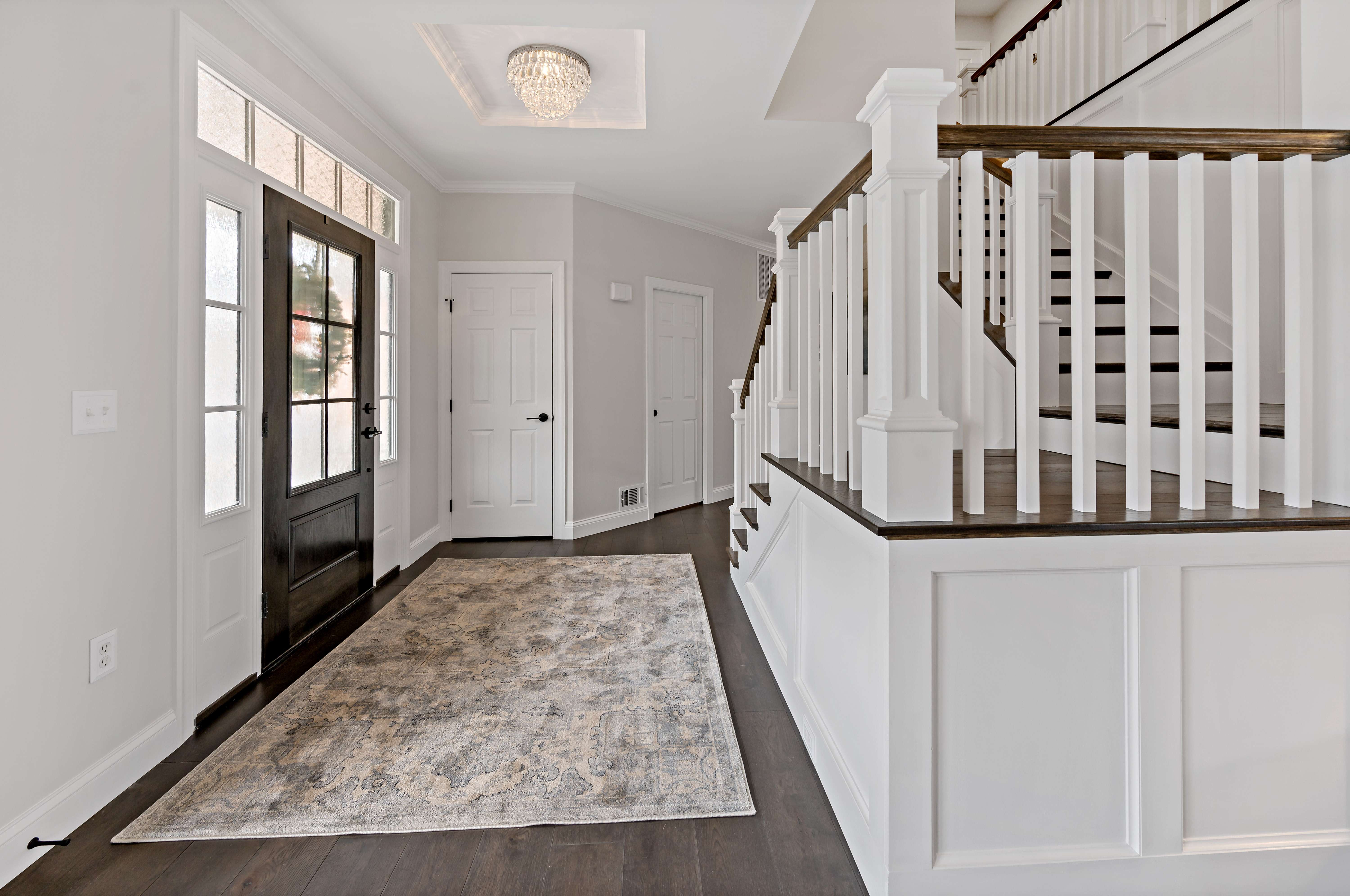 All white foyer with hard wood floors and stairs