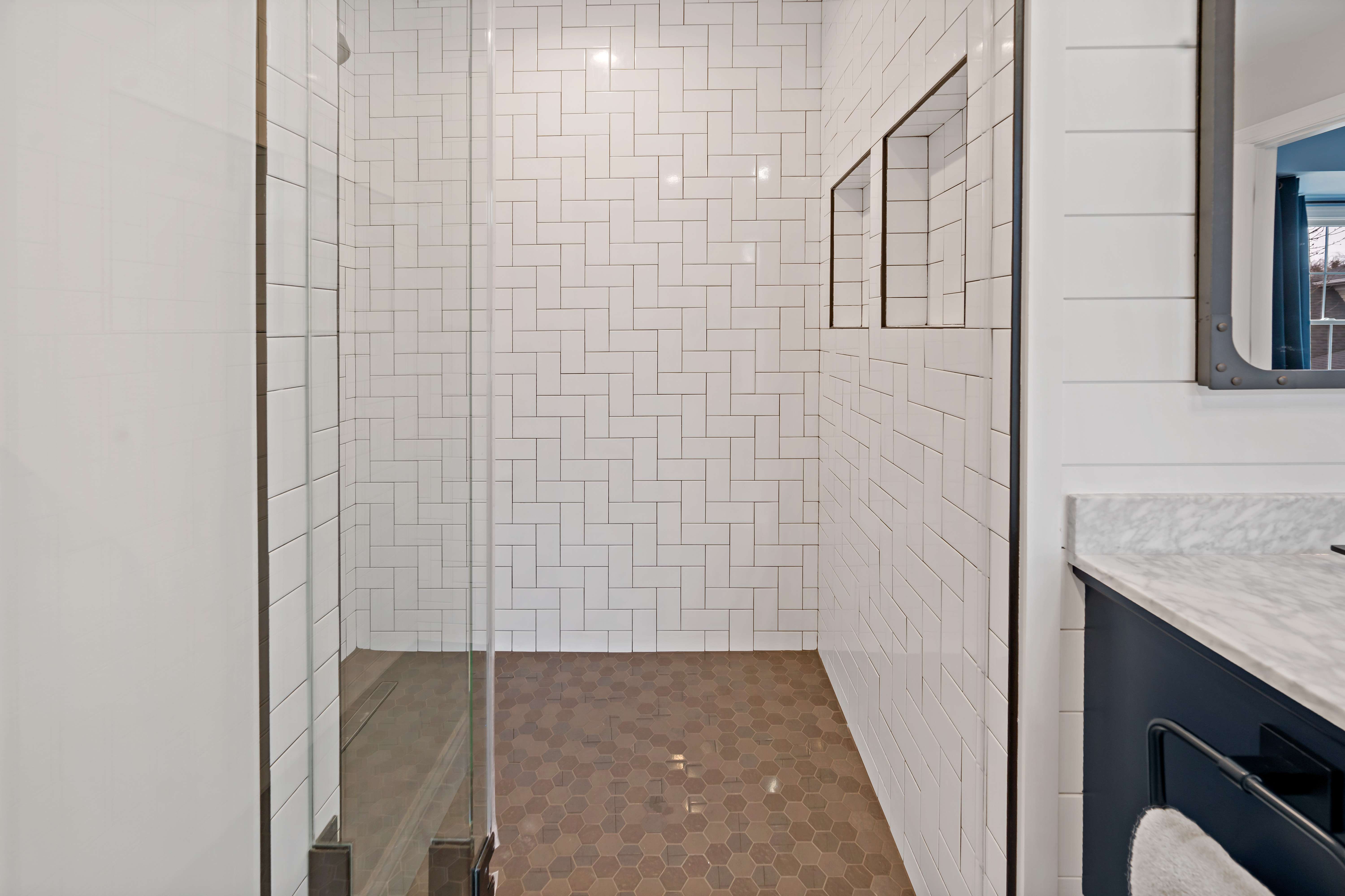 Brown shower tile floors and white tile walls