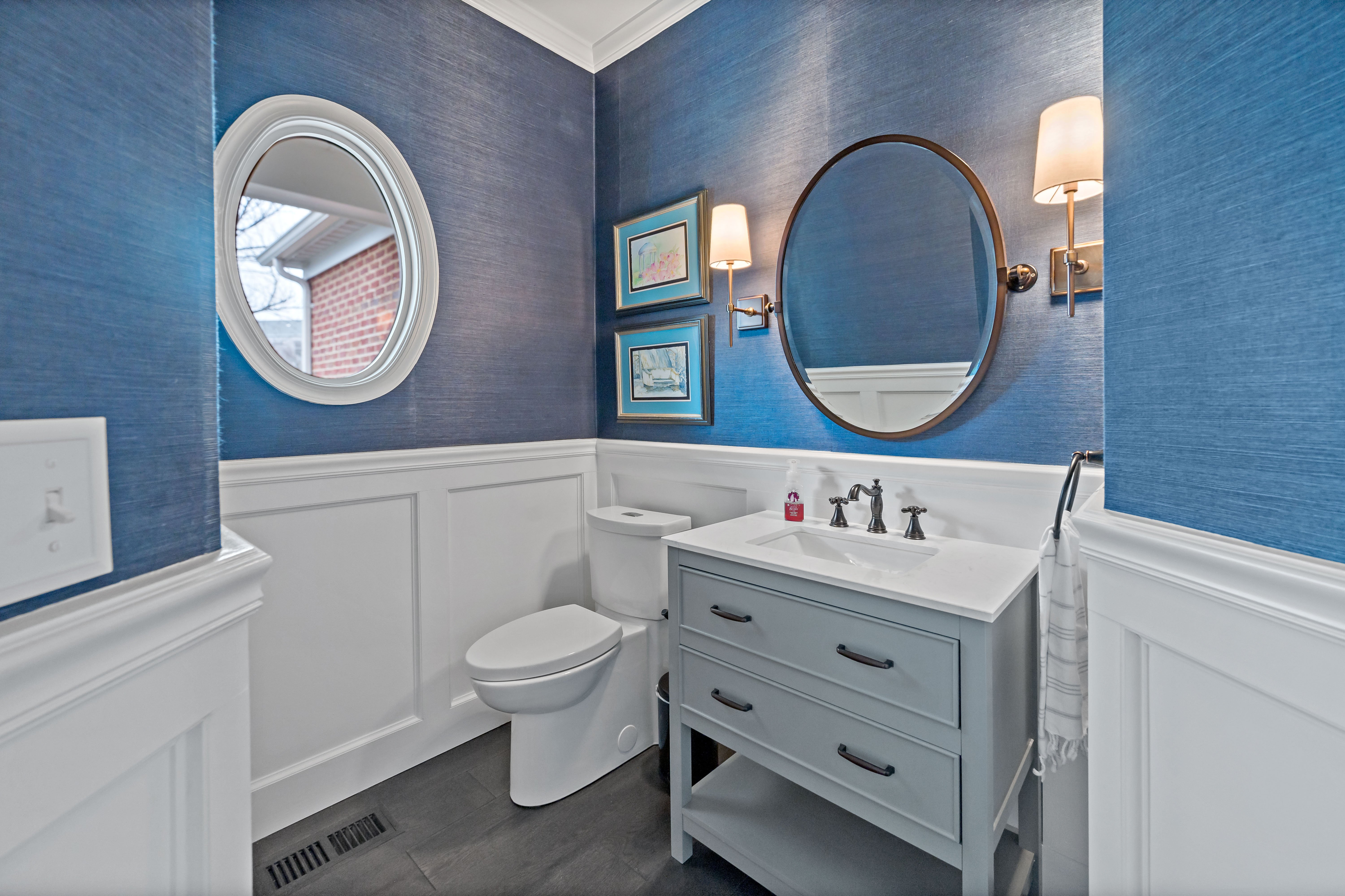Small bathroom with circular mirror and blue and white walls