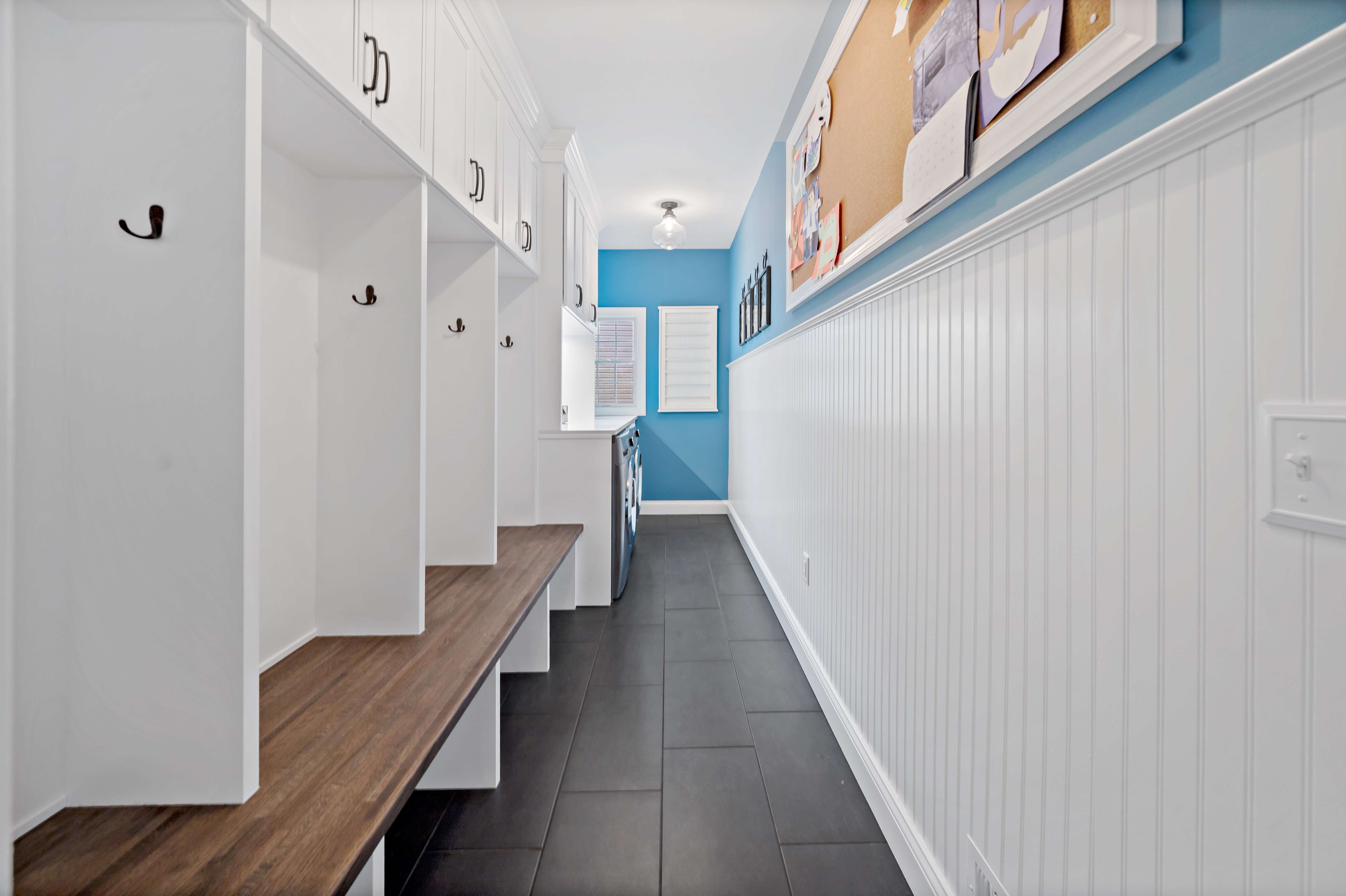 White mudroom with bench and dark grey floor tile