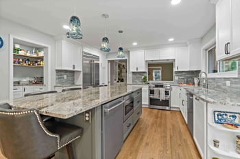 Two dish washers in kitchen with island and multicolored countertop