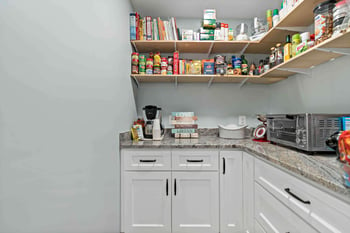 Walk-in kitchen pantry with floating shelves and white cabinets