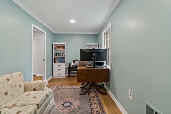 Home office with hard wood floors and rug with couch
