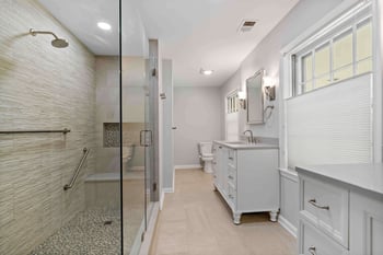 Master bathroom with double vanities and large, beige walk-in shower
