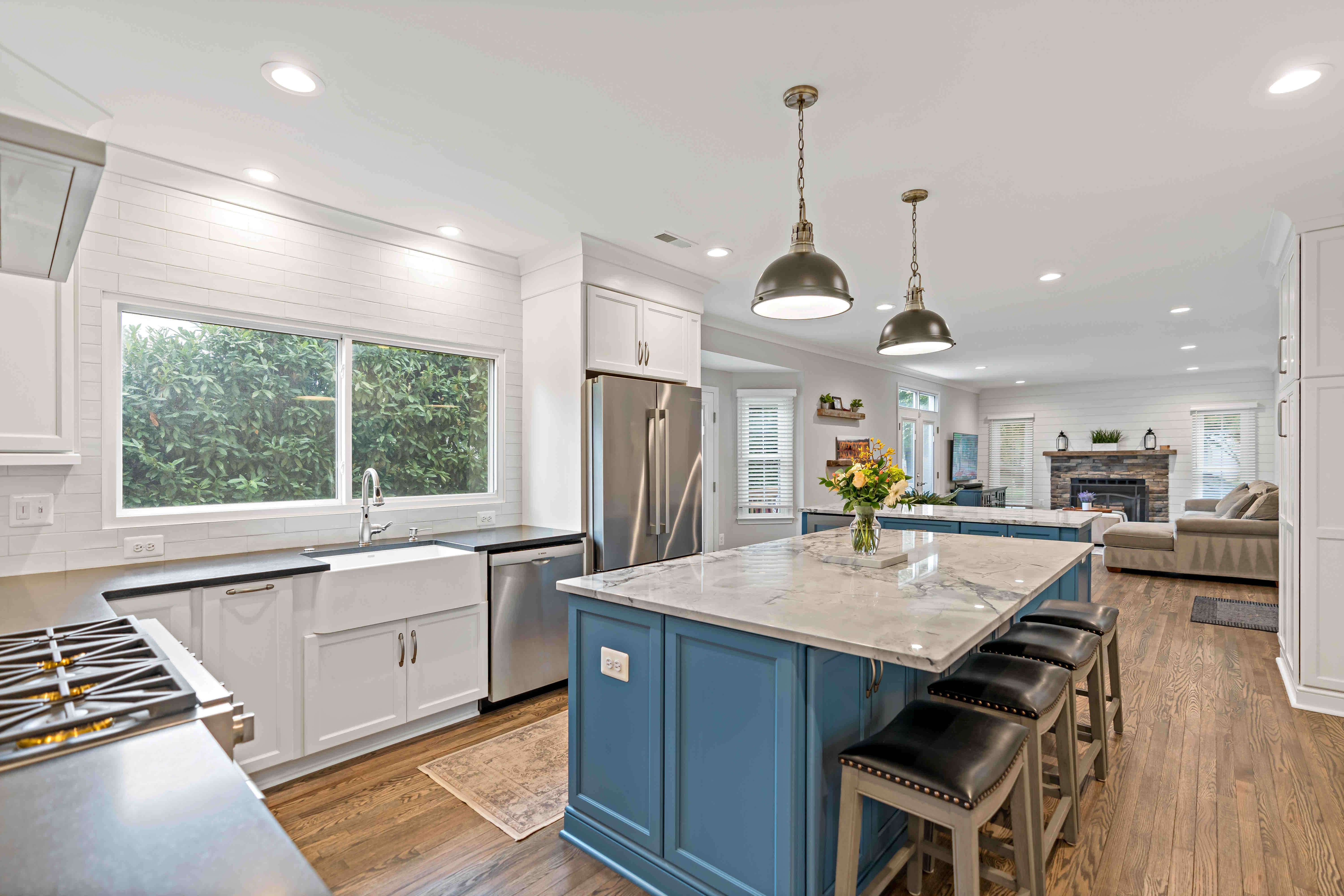 Blue island kitchen with white cabinets and pendant lighting