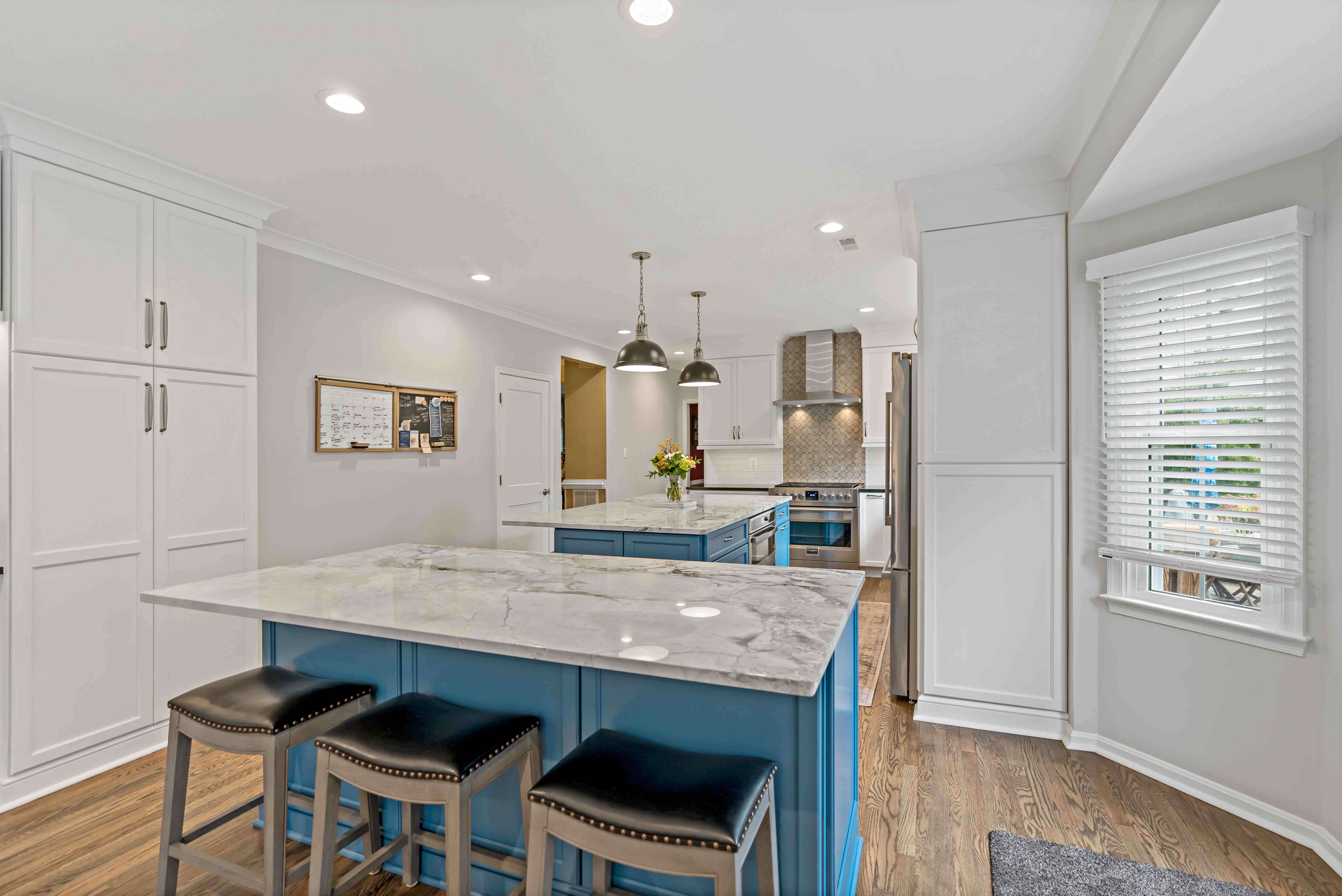 Two blue kitchen islands in all white kitchen