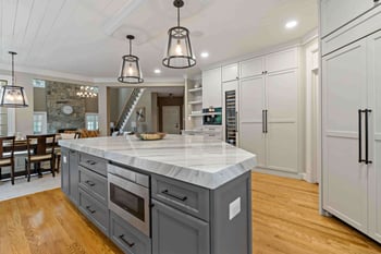 Open concept farmhouse kitchen with round pendant lighting above kitchen island