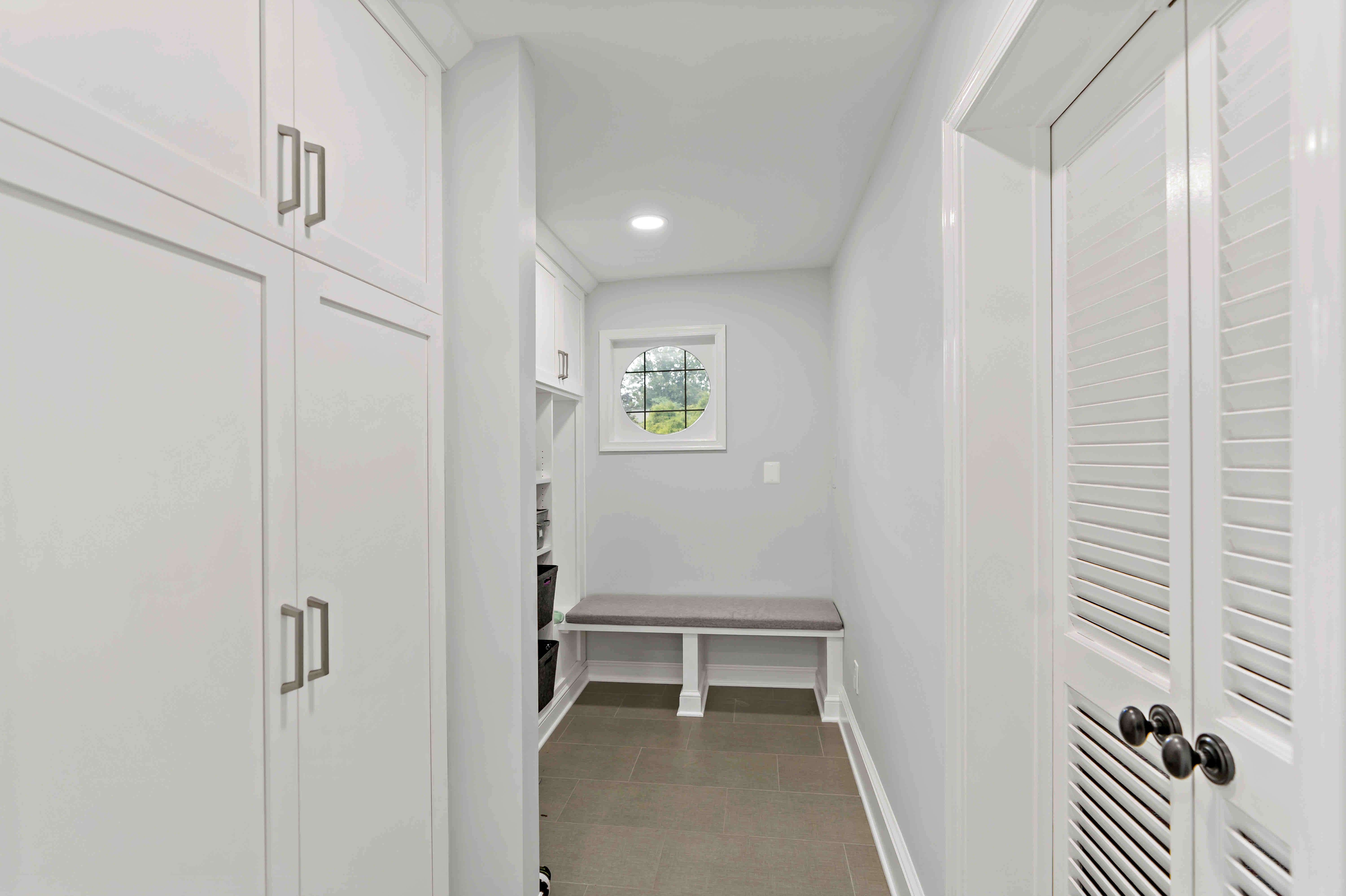 White mudroom with cabinets and bench