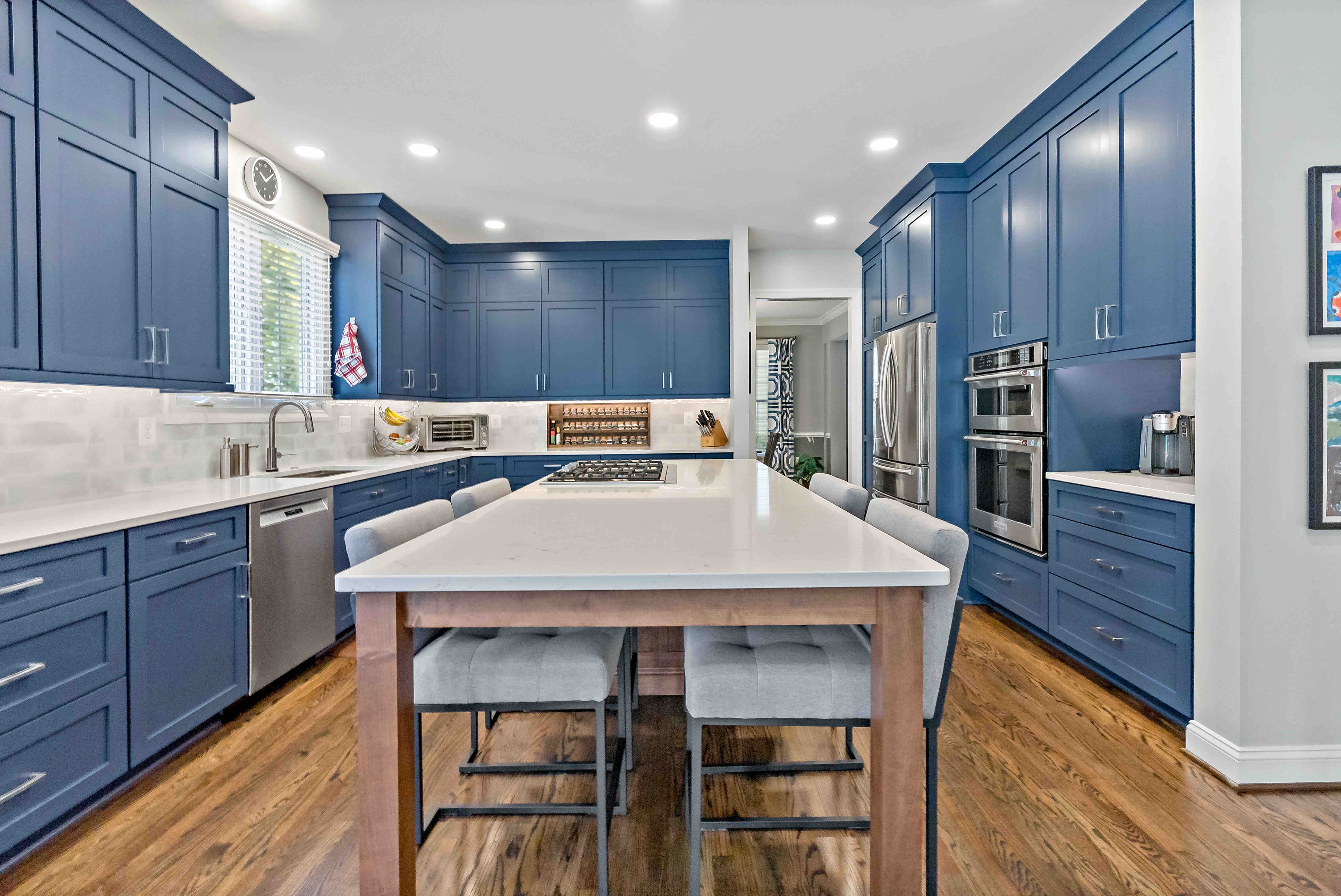 White countertop kitchen island with seating in blue kitchen