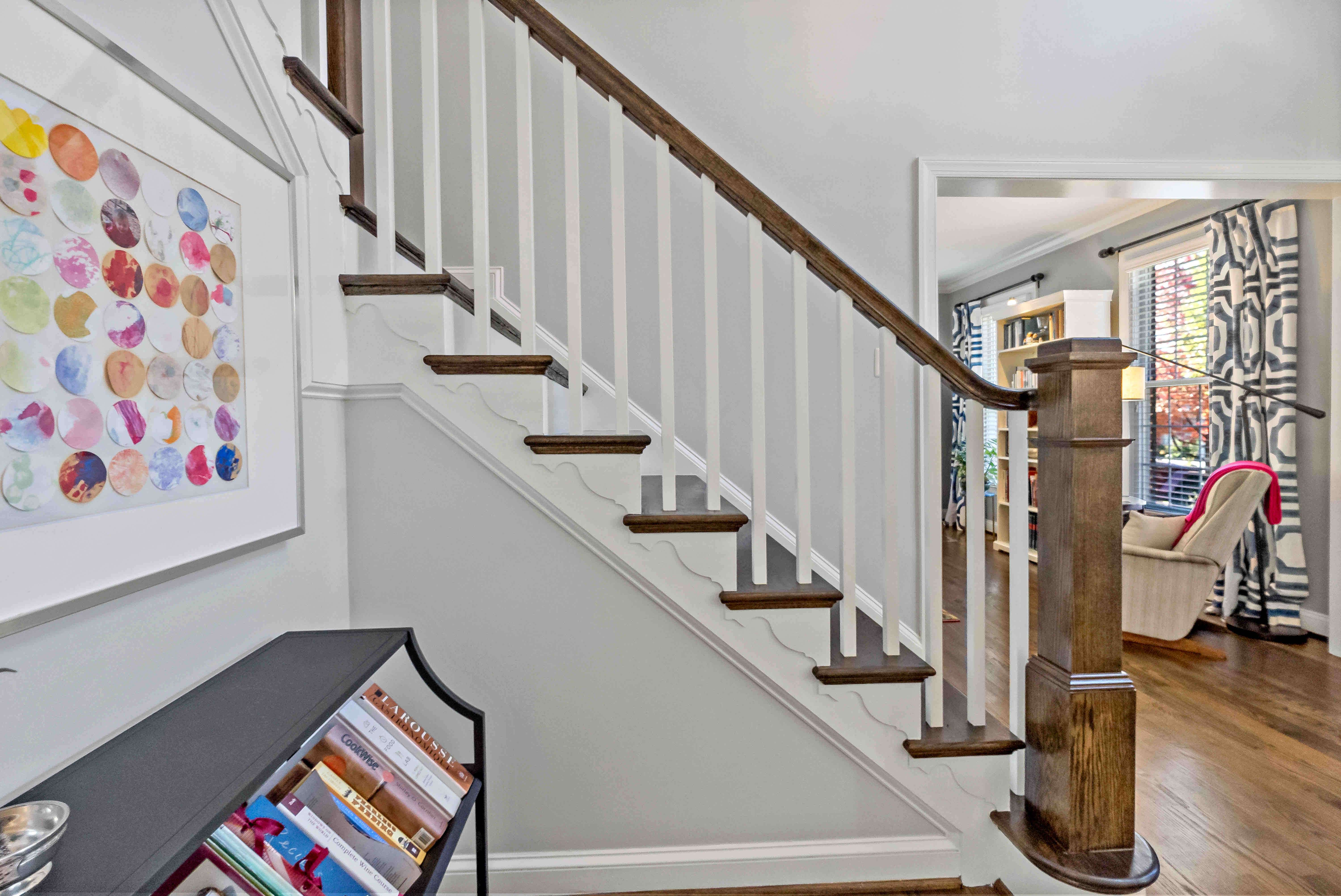 Side of stairwell with white bars and wood handle railing