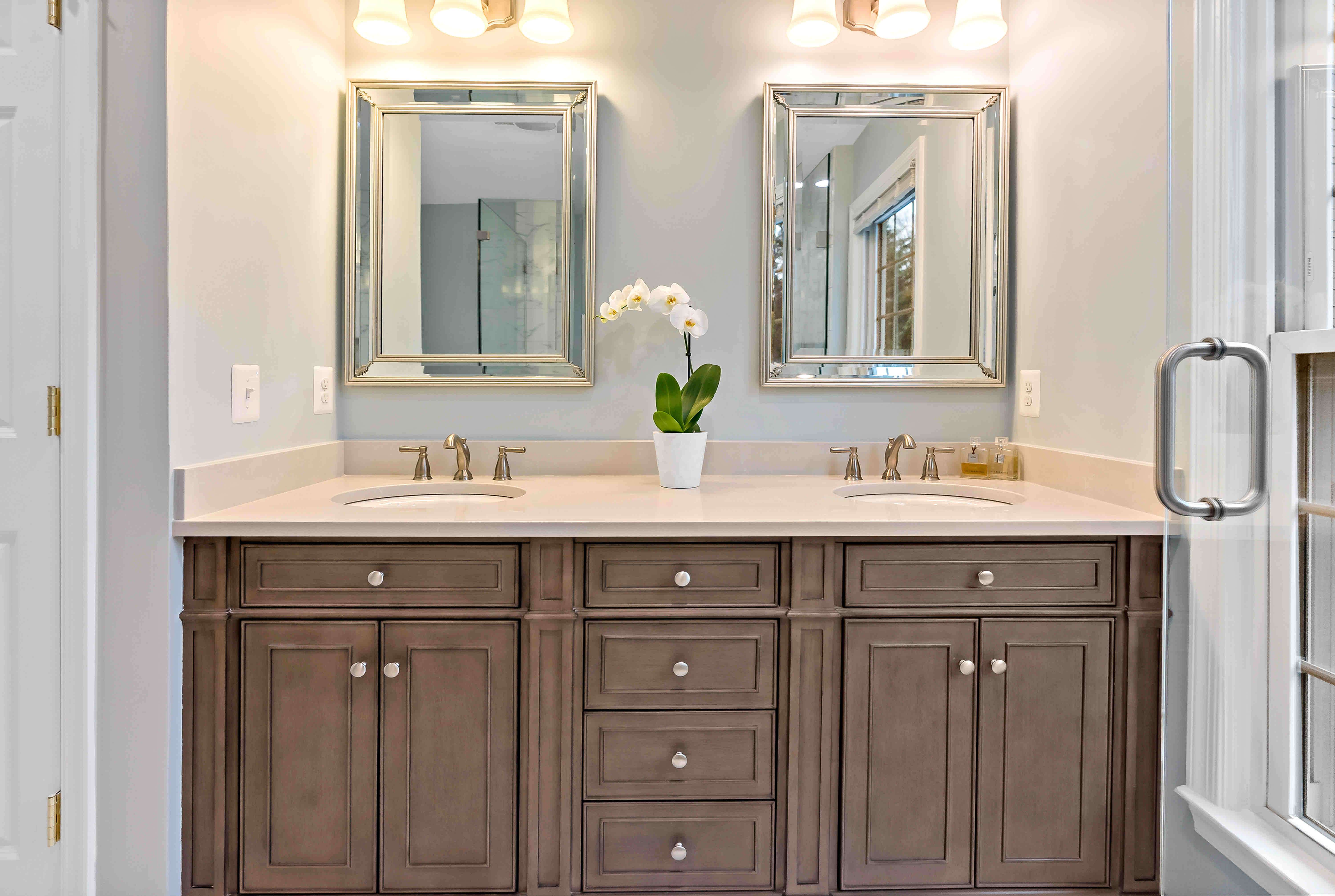 Double sink and vanity in full bathroom with brown cabinets