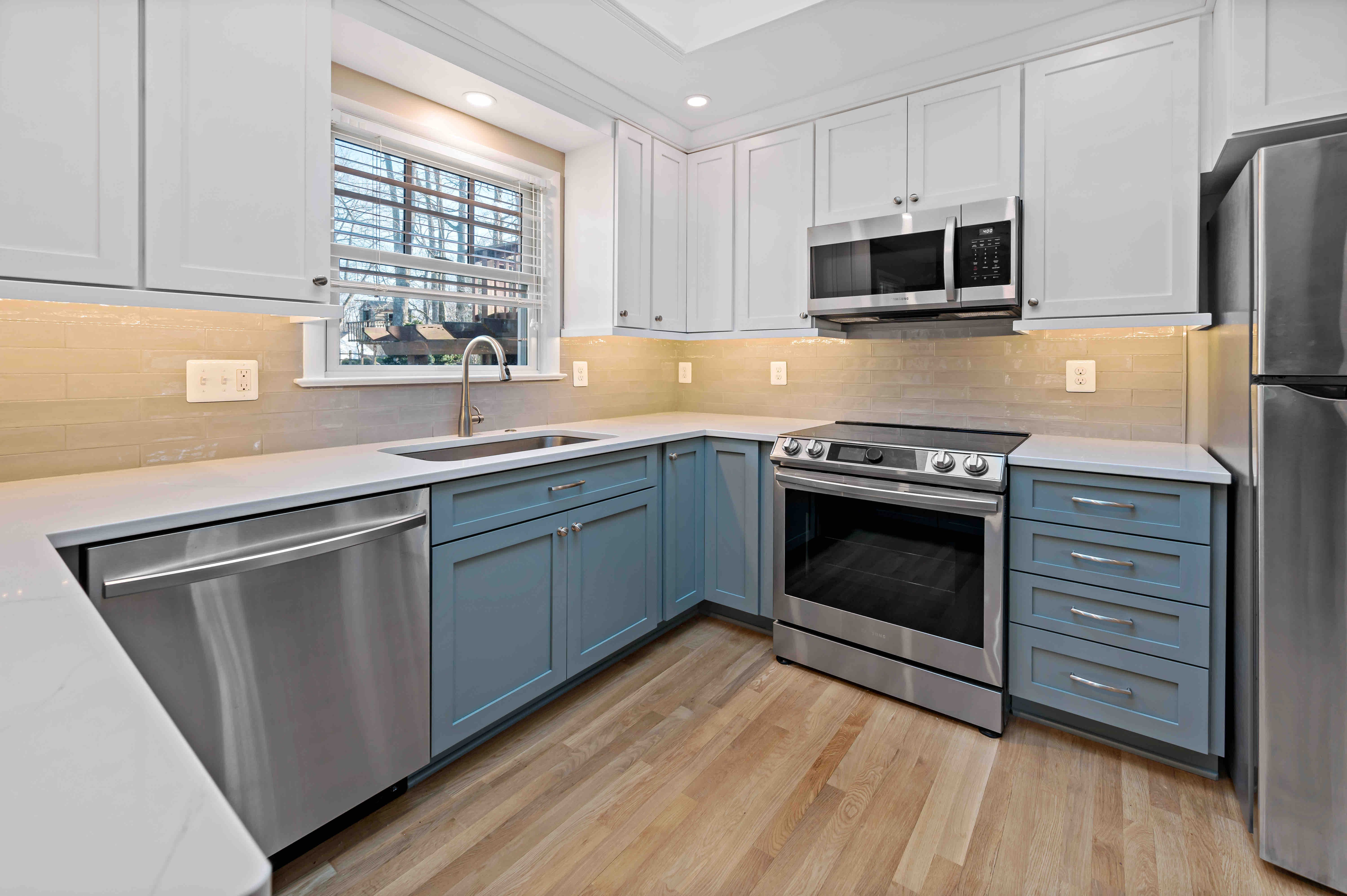 Spacious kitchen with hard wood floors and blue lower cabinets