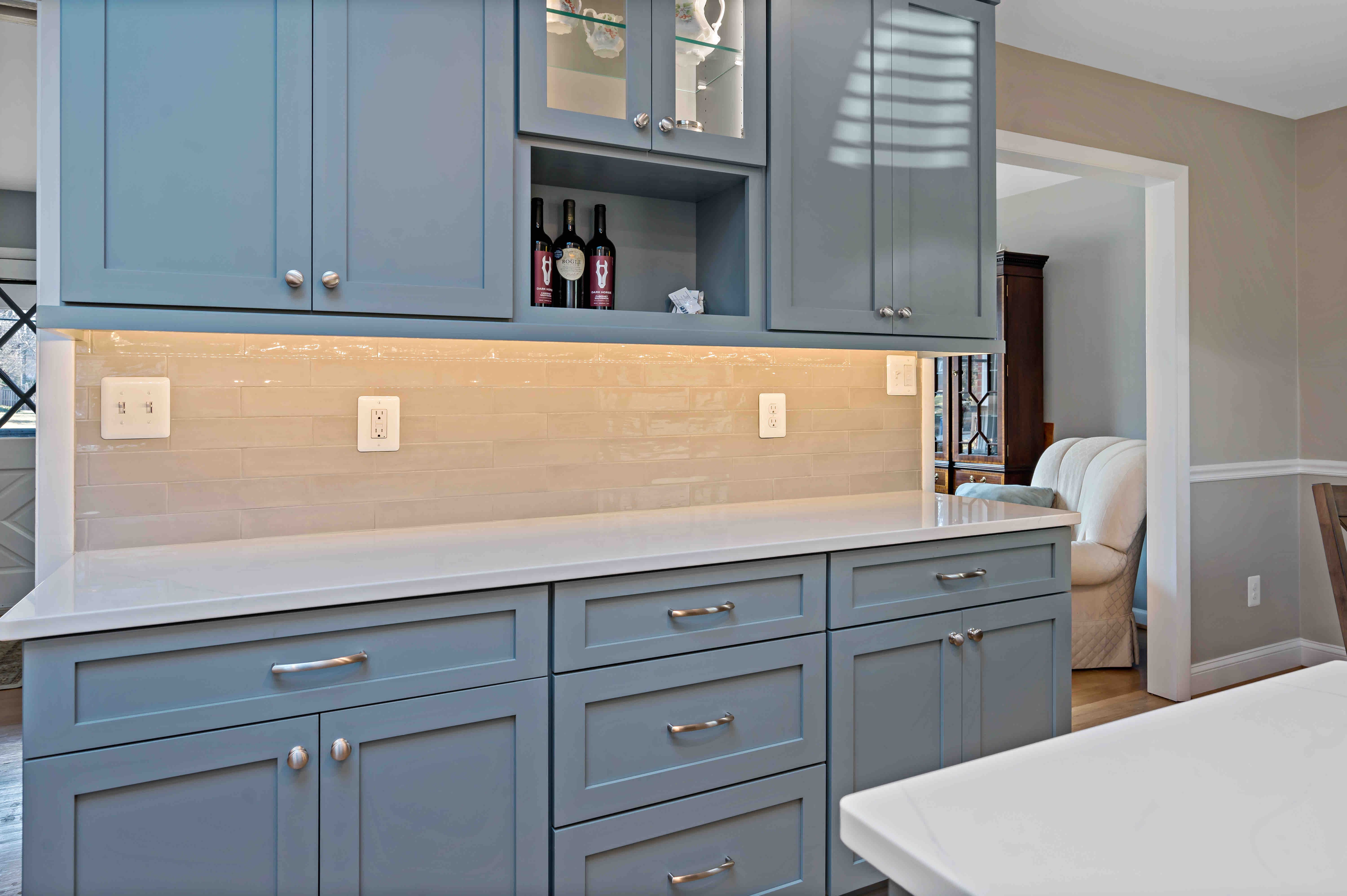 Light blue cabinets with white tile backsplash and under cabinet lighting