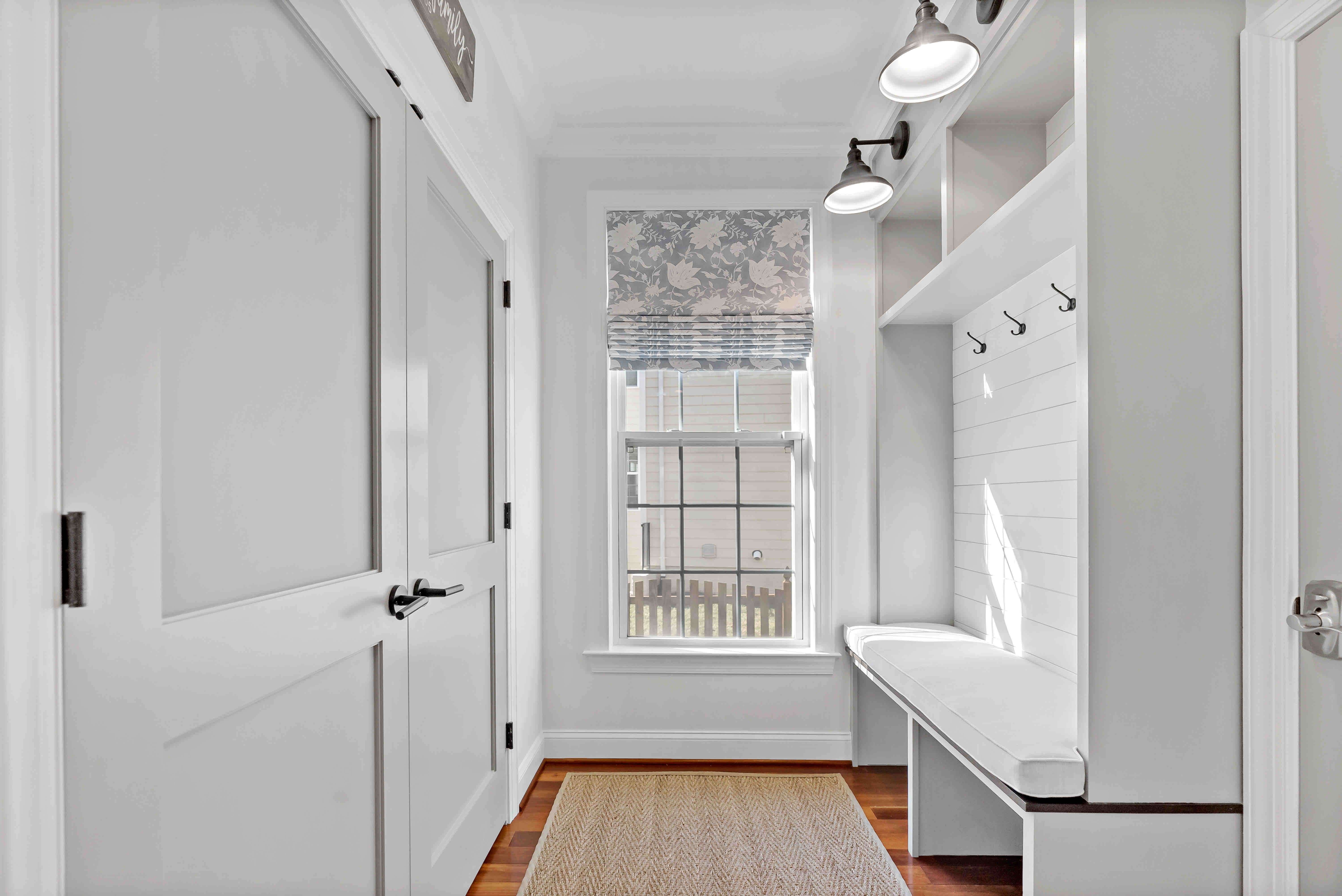 White mudroom with hooks and bench