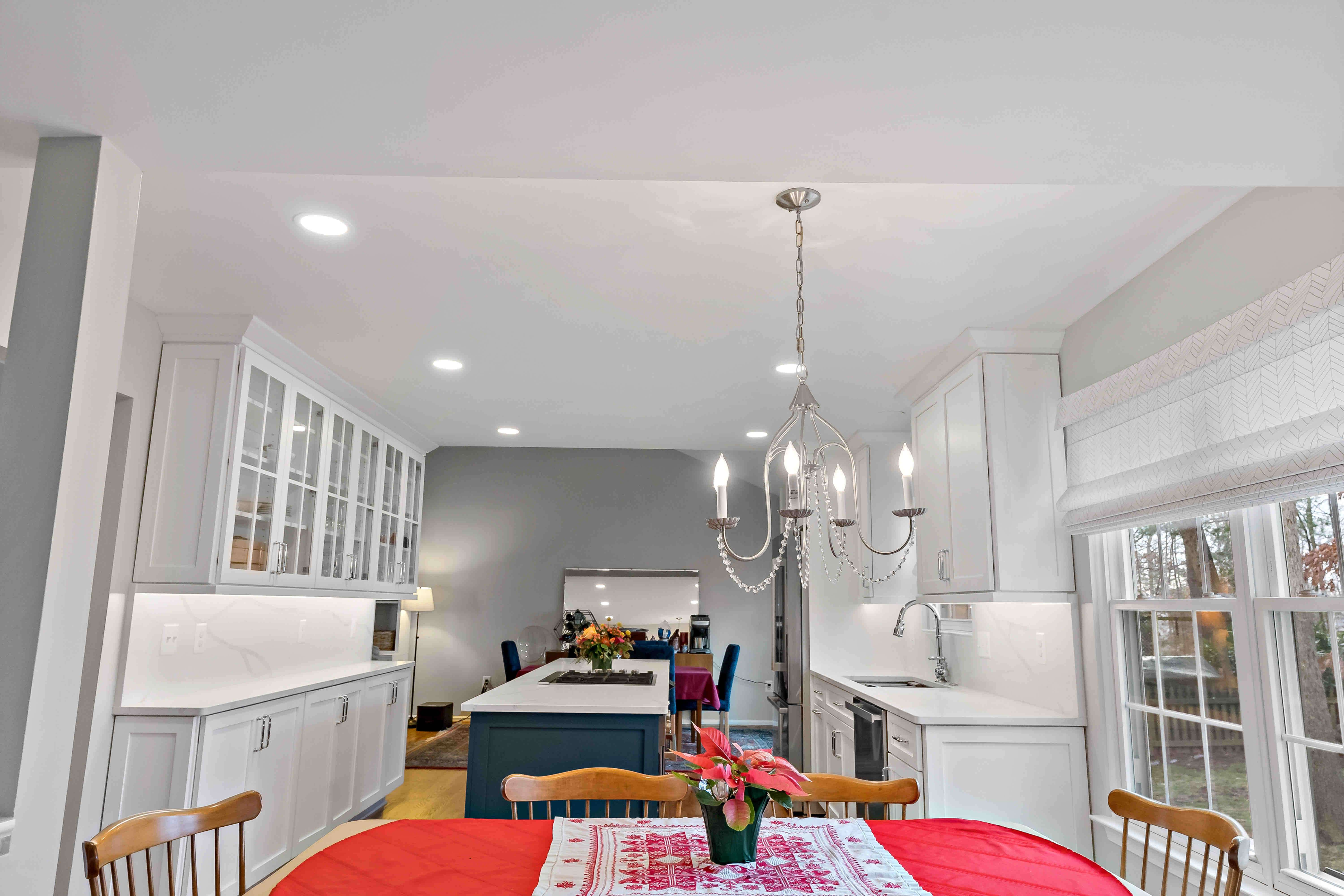 White chandelier above kitchen table in white kitchen