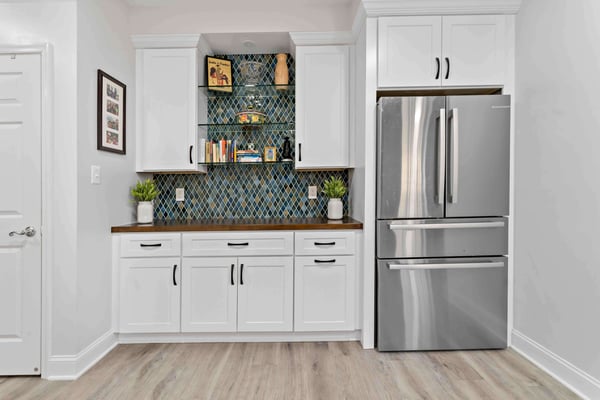 Basement fridge and counterspace with white cabinets and blue backsplash