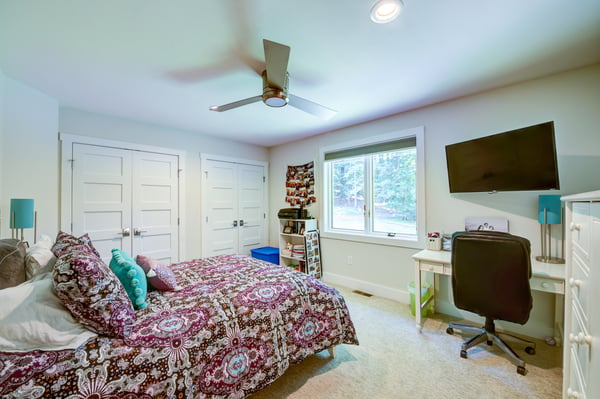 Carpeted bedroom with ceiling fan and desk space