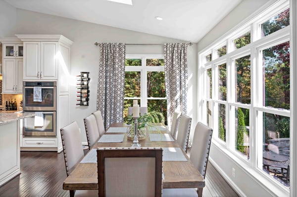 Brown and beige aesthetic in dining room with curtains and large windows for backyard views