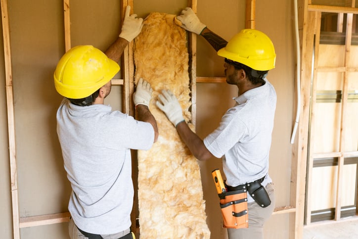 Construction workers fitting insulation for home remodel