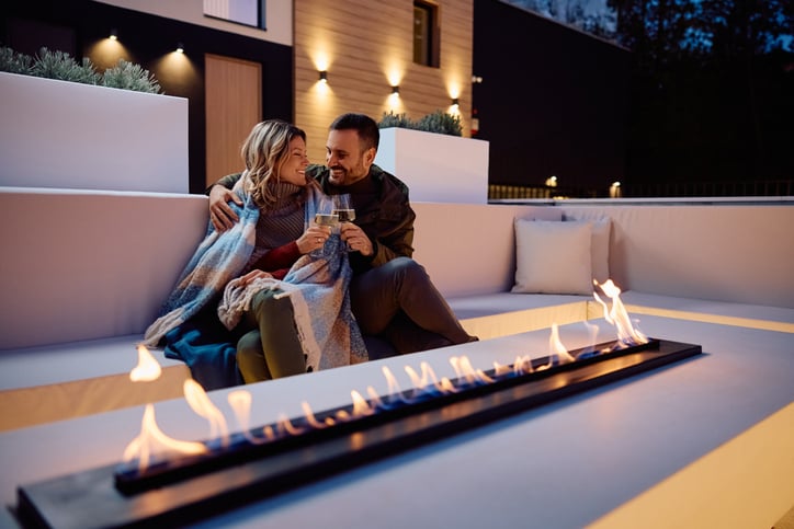 Happy couple toasting with wine on a patio in the evening.