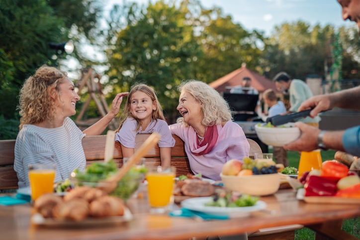 A happy, multigenerational gamily enjoying a meal together outdoors