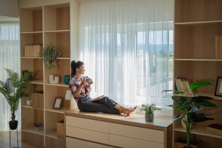 Young woman relaxing with coffee and book by window