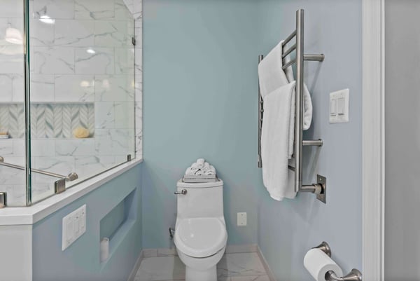 Light blue full bathroom with metal rack for towels