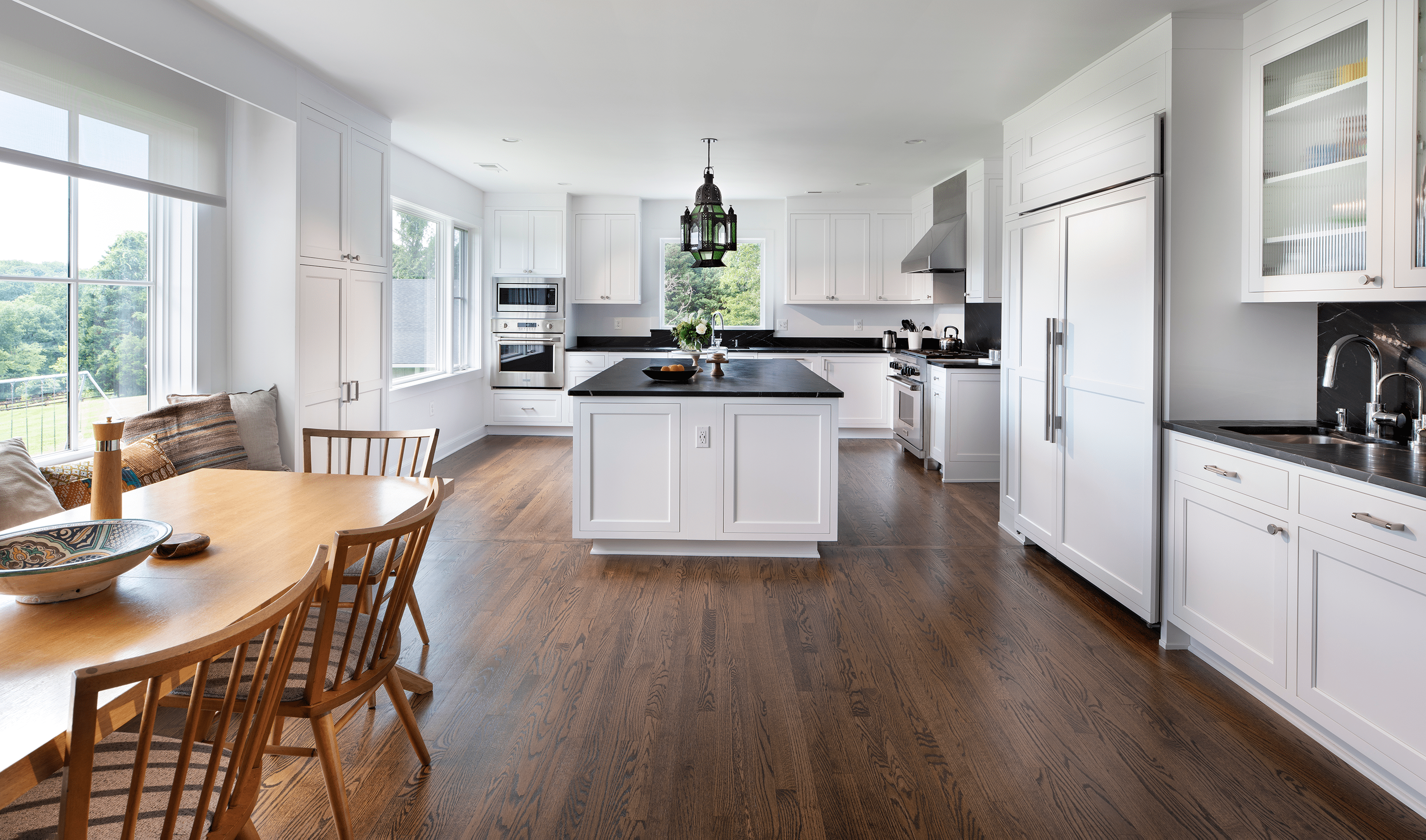 Dark wood flooring and white cabinets with black countertops in kitchen