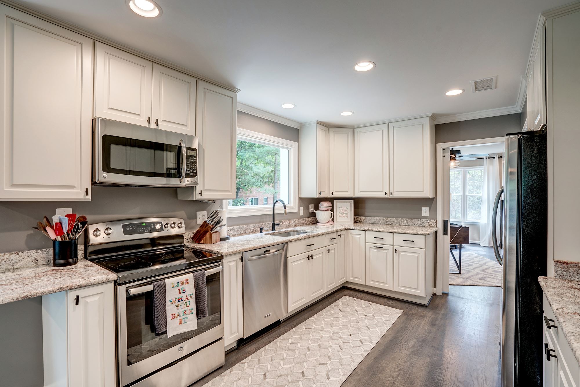 White kitchen cabinets and granite counters with wood floors