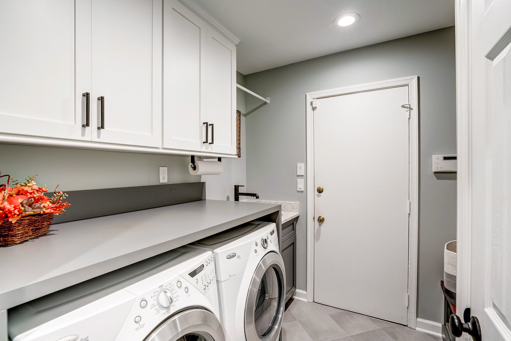 Laundry room with white cabinets and tile floors