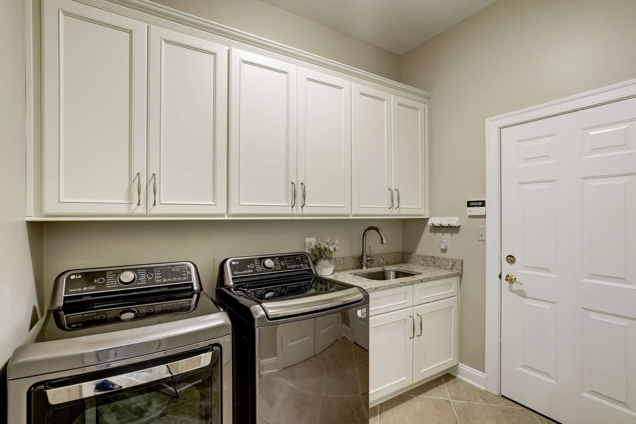Laundry room with white cabinets and sink
