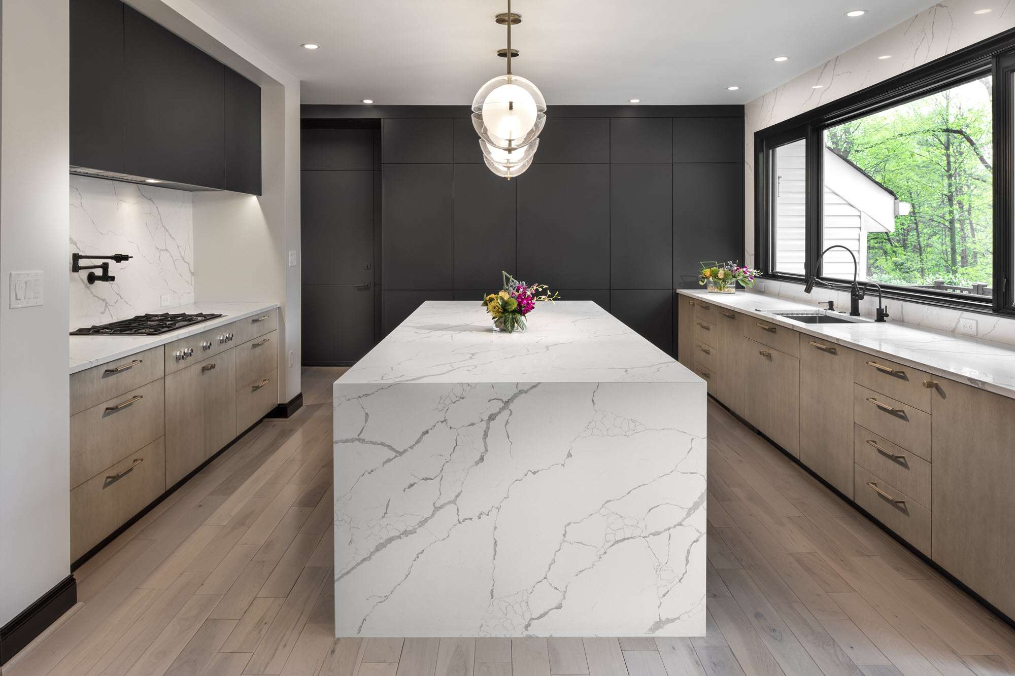 Large modern island with marble top and brown cabinets in kitchen