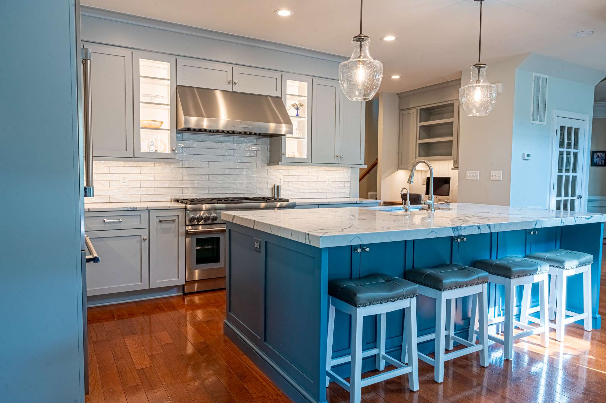 Grey cabinets and white tile backsplash in kitchen with blue island
