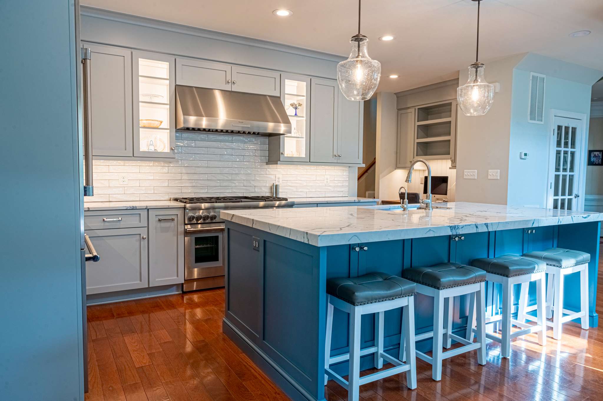 Grey cabinets and white tile backsplash in kitchen with blue island