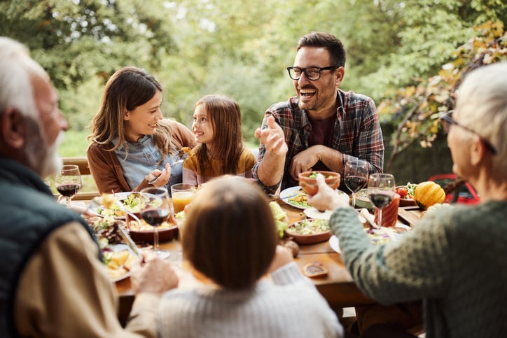 Happy multi-generation family enjoying in conversation while having a meal in nature.