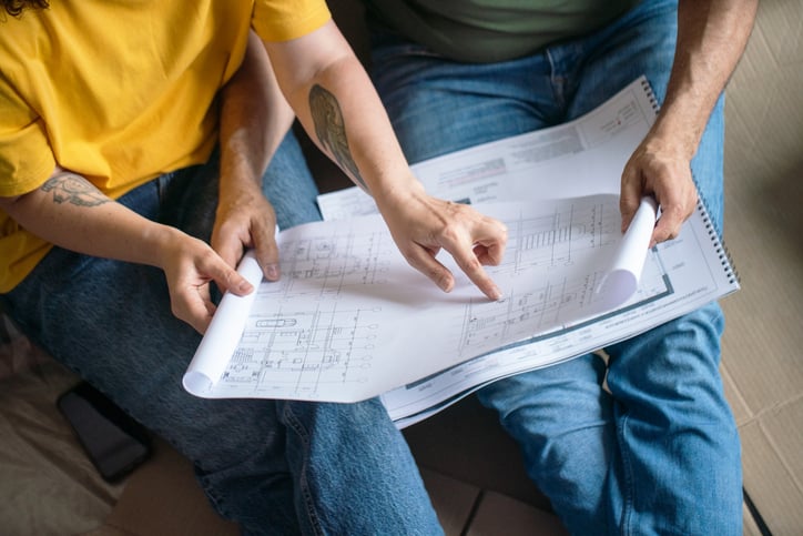 Homeowners examining and discussing construction blueprints and considering a home remodeling project